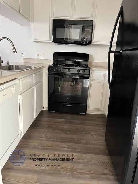 a kitchen with white cabinets and a black stove and microwave